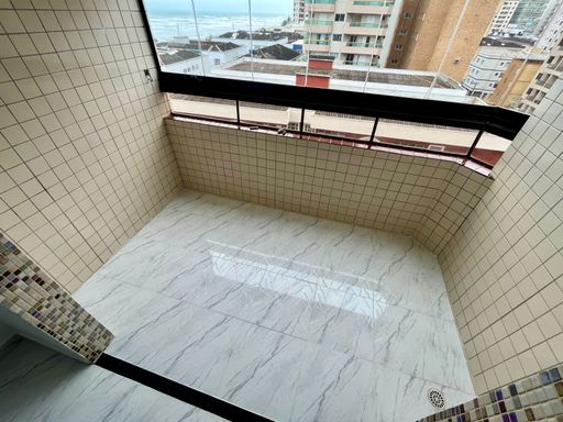 Sacada envidraçada da sala com vista para o mar.