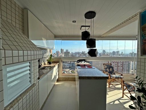 Sacada gourmet envidraçada com vista para o mar.