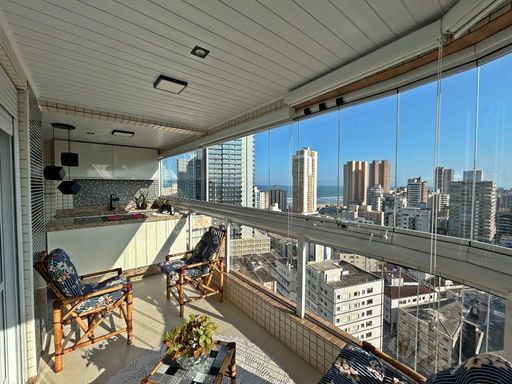 Sacada gourmet envidraçada com vista para o mar.