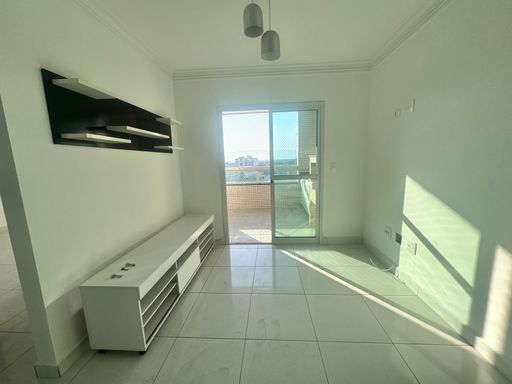 Sala de 2 ambientes com painel de TV e paredes brancas e acesso a sacada gourmet.
