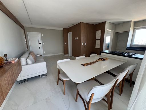 Sala ampla e bem iluminada de dois ambientes com mesa de jantar e sofá.