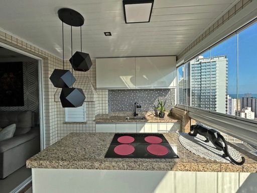 Sacada gourmet envidraçada com vista para o mar.