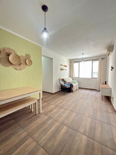 Sala ampla e bem iluminada com uma janela com vista lateral para o mar.