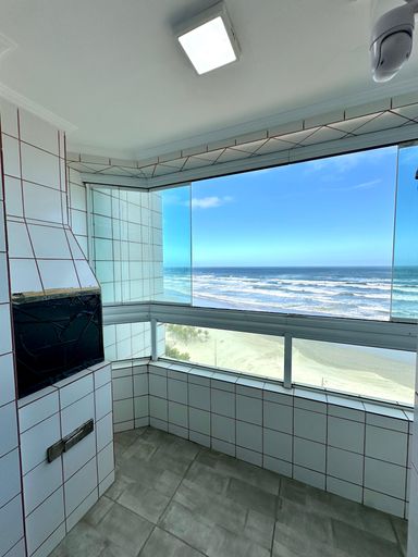 Sacada gourmet envidraçada com vista para o mar.