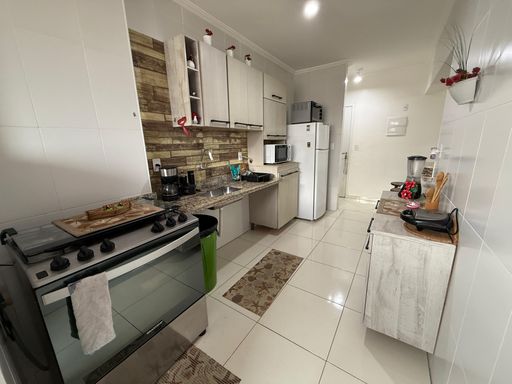 Cozinha americana planejada com fogão e geladeira branca.