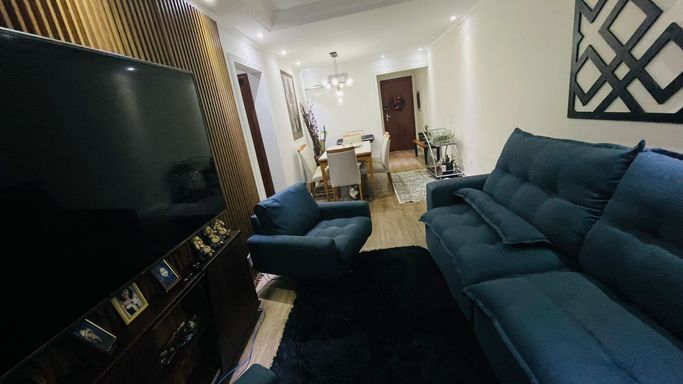 Sala de 2 ambientes com painel ripado, lustre pendente e ar-condicionado.