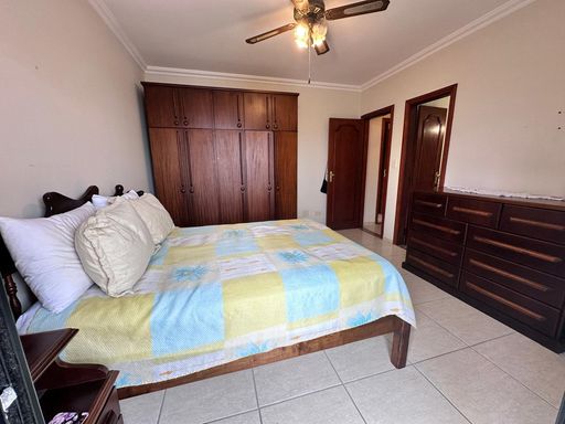 Suíte muito bem iluminado com uma cama de casal com uma sacada privativa e ventilador de teto.