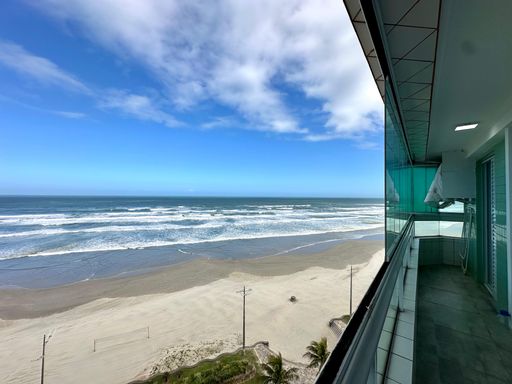 Sacada gourmet envidraçada com vista para o mar.