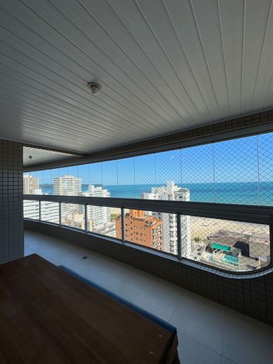 Sacada gourmet envidraçada com vista para o mar.