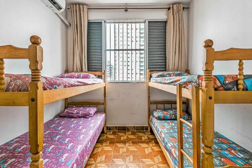 Dormitório bem iluminado, com dois beliches e ar-condicionado.