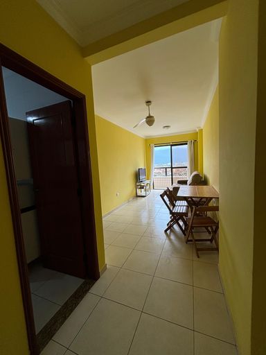 Sala de 2 ambientes com paredes amarelas, mesa, sofa e ventilador de teto.
