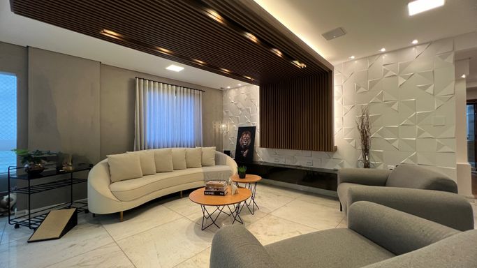 Sala ampla com dois ambientes, equipada com lustre pendente, mesa para oito pessoas, sofá, duas poltronas, ar-condicionado, teto rebaixado com iluminação em LED e sacada envidraçada.