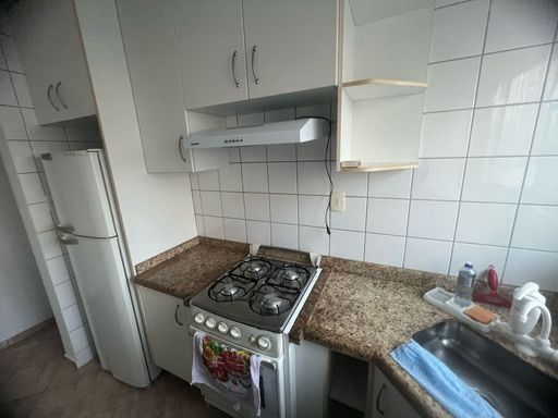 Cozinha americana com armários planejados, geladeira e fogão.