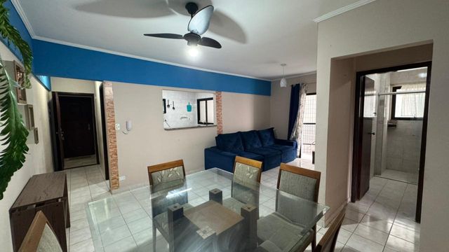 Sala de 2 ambientes com um sofá, mesa de jantar, painel de TV, ventilador de teto.