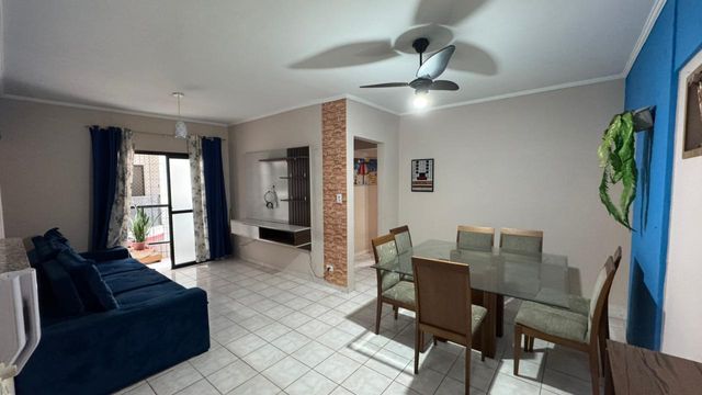 Sala de 2 ambientes com um sofá, mesa de jantar, painel de TV, ventilador de teto.