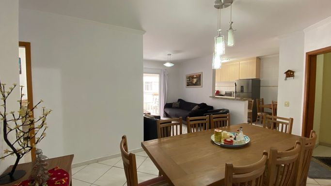 Sala de 2 ambientes com uma mesa de jantar e sofá.