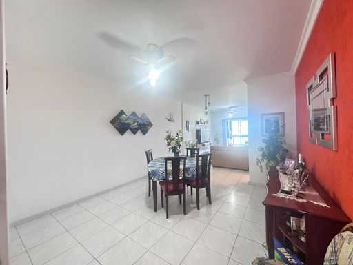 Sala bem iluminada de dois ambientes com mesa de jantar e ventilador de teto.
