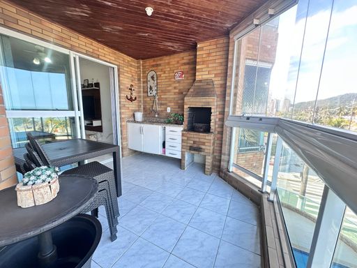 Sacada gourmet envidraçada com vista para o mar.