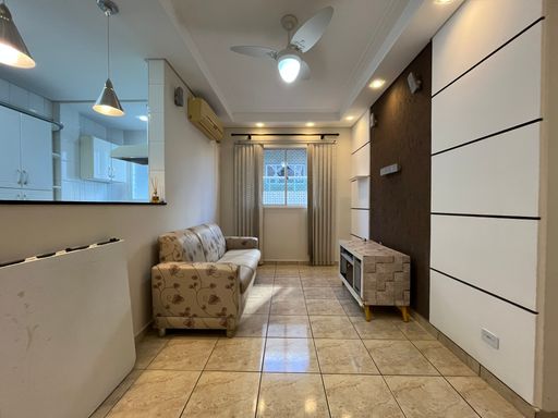 Sala com muita iluminação natural, sofá, ventilador de teto e ar-condicionado.