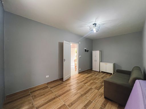 Dormitório amplo com sofá e ventilador de teto.