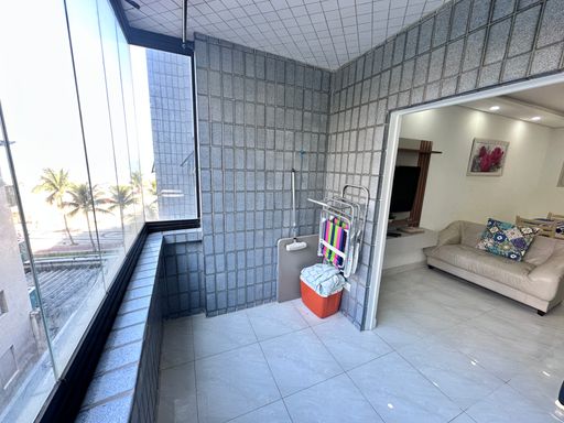 Sacada envidraçada com vista para o mar.