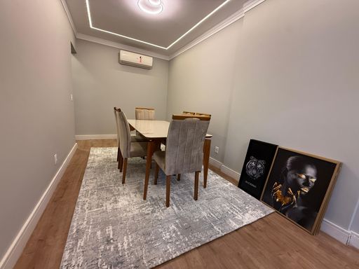 Sala de dois ambientes com sofá, mesa de jantar, TV e ar-condicionado.