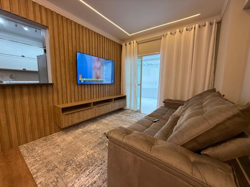 Sala de dois ambientes com sofá, mesa de jantar, TV e ar-condicionado.