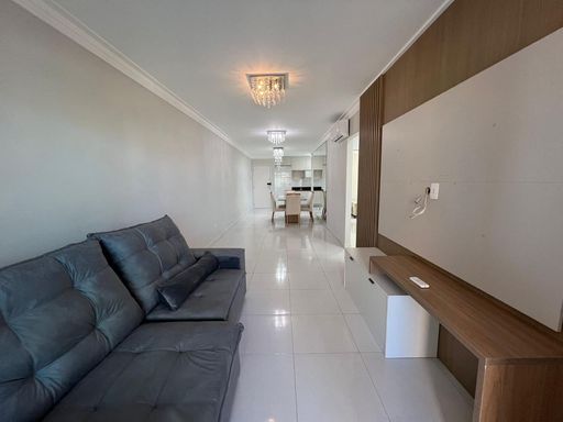 Sala com dois ambientes, ar-condicionado, lustre pendente e parede espelhada.