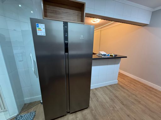 Cozinha americana planejada com uma geladeira Inox de duas portas.