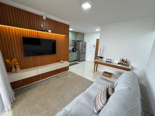 Sala ampla com painel de TV, com acesso a sacada gourmet.