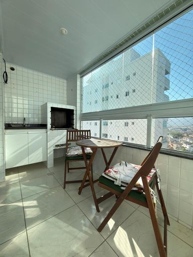 Sacada gourmet envidraçada com churrasqueira a carvão e vista livre.