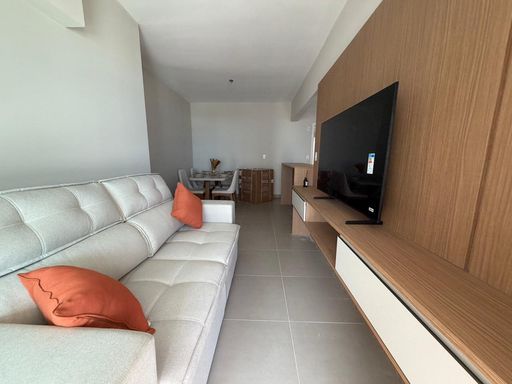 Sala de dois ambientes com um sofá e painel de TV.