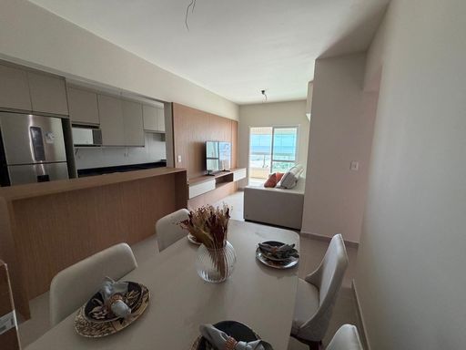 Sala de dois ambientes com um sofá e painel de TV.