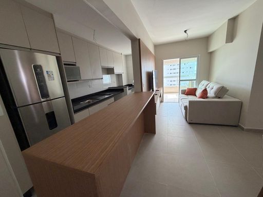 Sala de dois ambientes com um sofá e painel de TV.