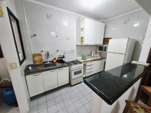 Cozinha americana com armários brancos e fogão.