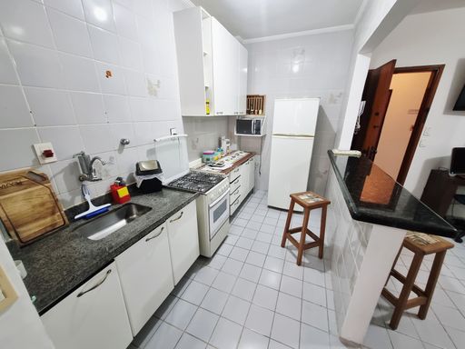 Cozinha americana com armários brancos e fogão.