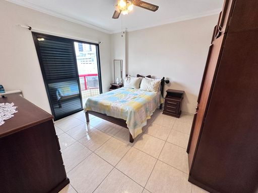 Suíte muito bem iluminado com uma cama de casal com uma sacada privativa e ventilador de teto.