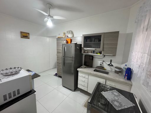 Cozinha mobiliada com armários, geladeira, fogão e ventilador de teto.