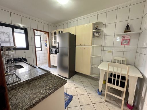Cozinha com armários brancos, pia, gabinete e geladeira.