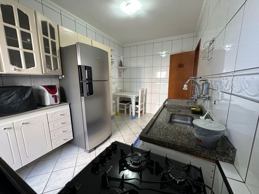 Cozinha com armários brancos, pia, gabinete e geladeira.