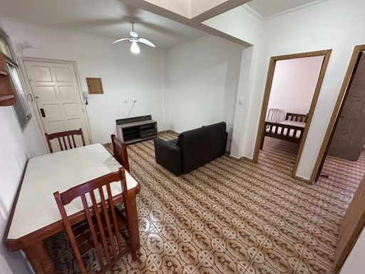 Sala ampla e bem iluminada com um ventilador de teto, sofá e mesa de jantar.