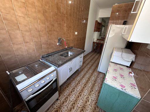 Cozinha com uma geladeira, pia e fogão.