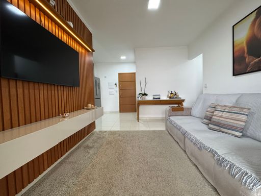 Sala ampla com painel de TV, com acesso a sacada gourmet.