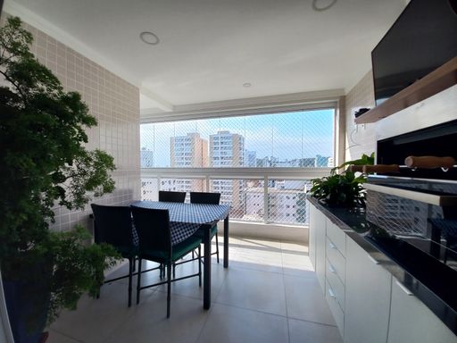 Sacada gourmet envidraçada com vista parcial para o mar.