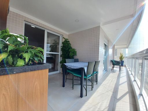 Sacada gourmet envidraçada com vista parcial para o mar.