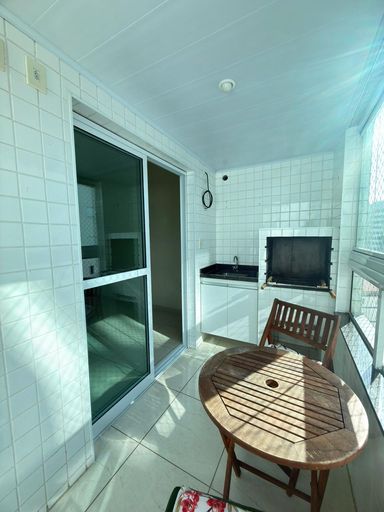 Sacada gourmet envidraçada com churrasqueira a carvão e vista livre.