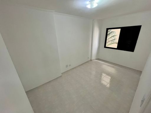 Dormitório espaçoso com paredes brancas.