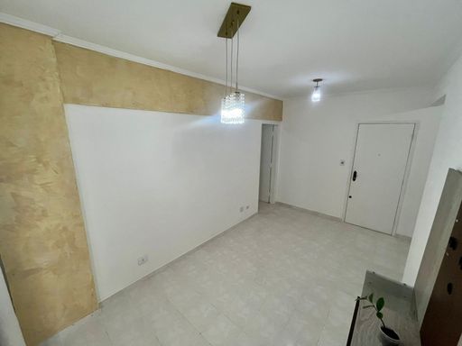 Sala espaçosa com paredes brancas, painel de TV e uma sacada.