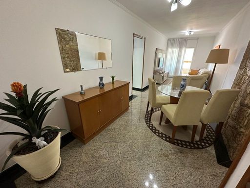 Sala de dois ambientes com muita iluminação natural, mesa de jantar e sofá.