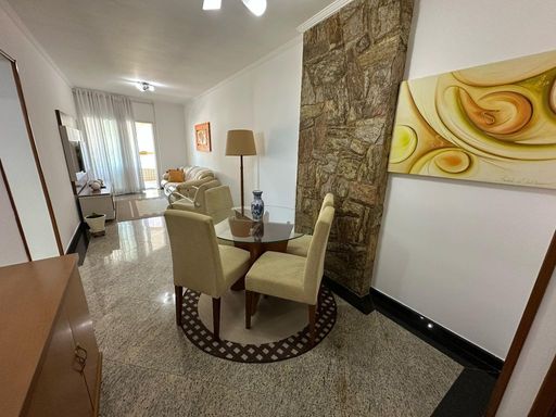 Sala de dois ambientes com muita iluminação natural, mesa de jantar e sofá.